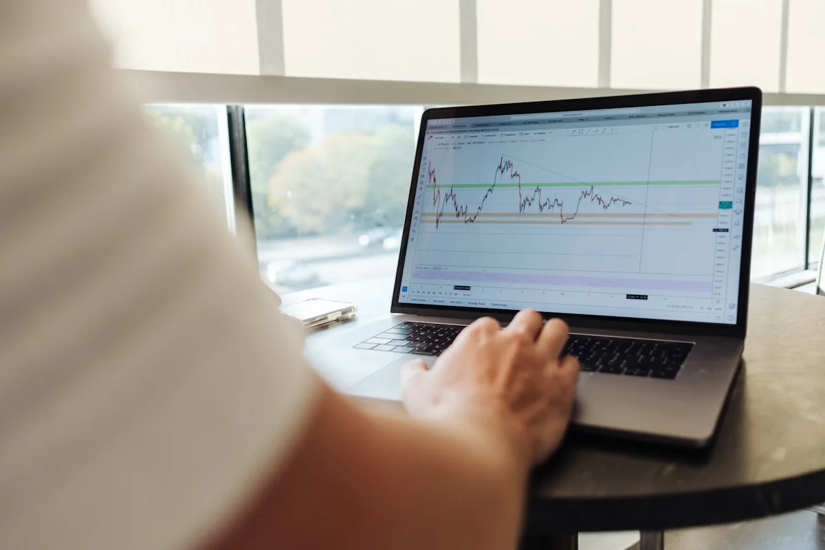 Swing trader holding a multi-day crypto position, monitoring price action across sessions from a desk setup with daily and weekly charts visible