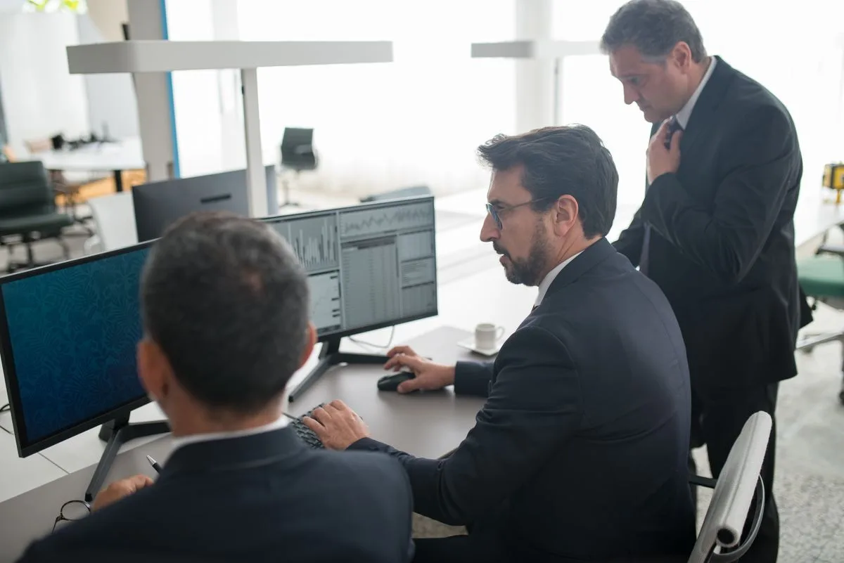 Two traders reviewing market data on multiple monitors at a trading desk