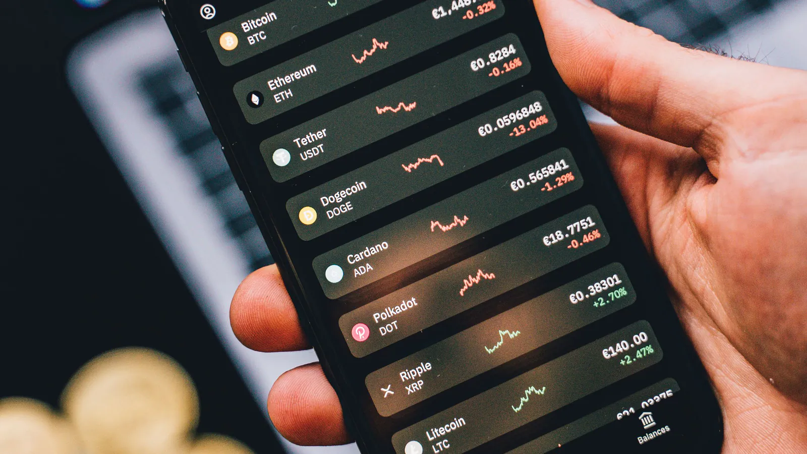 A phone showing a list of crypto prices next to a laptop