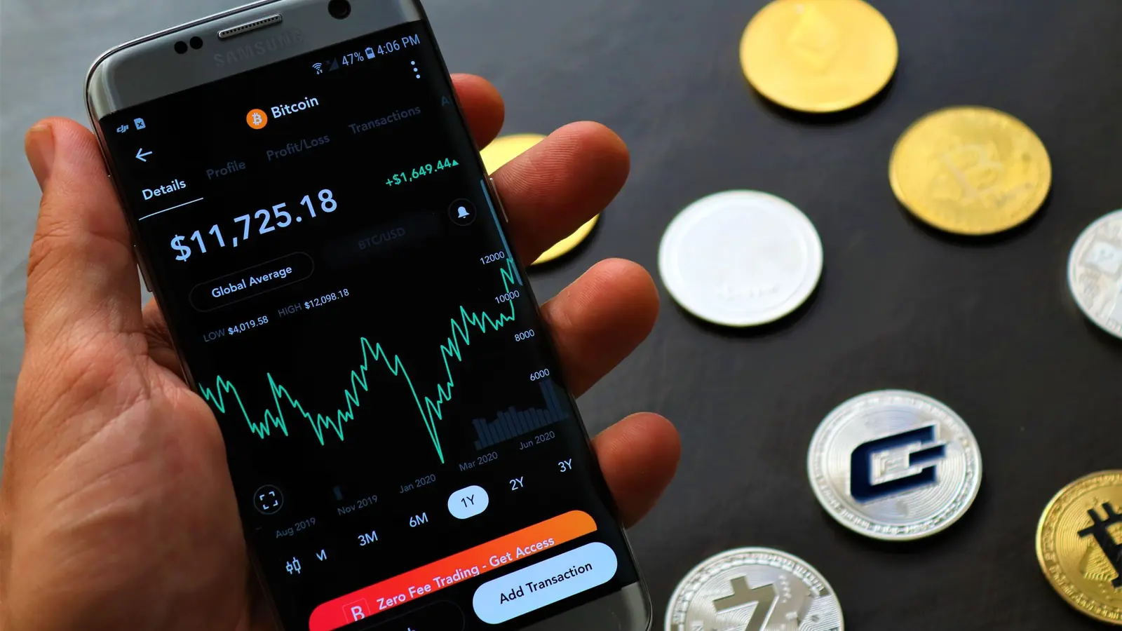 A phone showing a crypto trading app next to coins