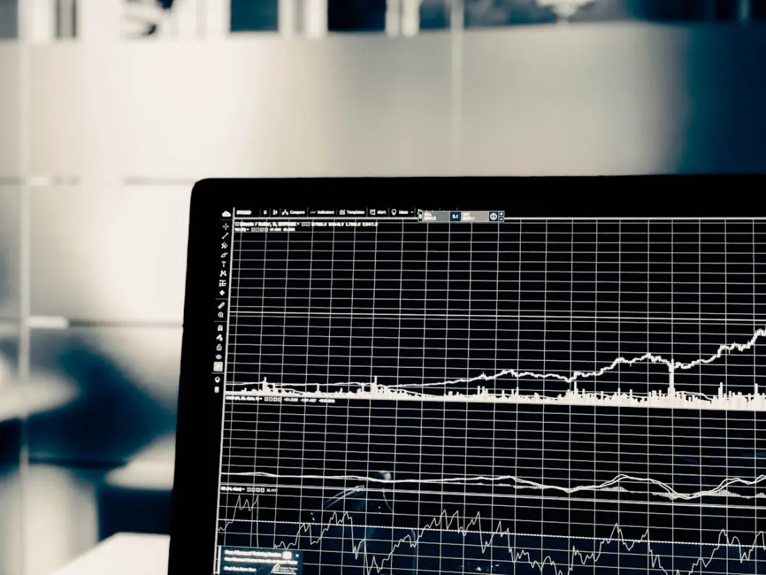 A laptop screen displaying a financial trading chart with grid lines and indicators