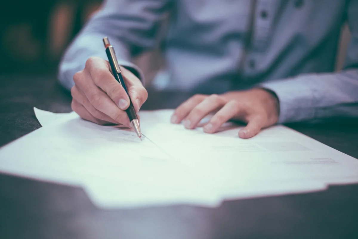 Person reviewing contract terms and conditions documents at a desk