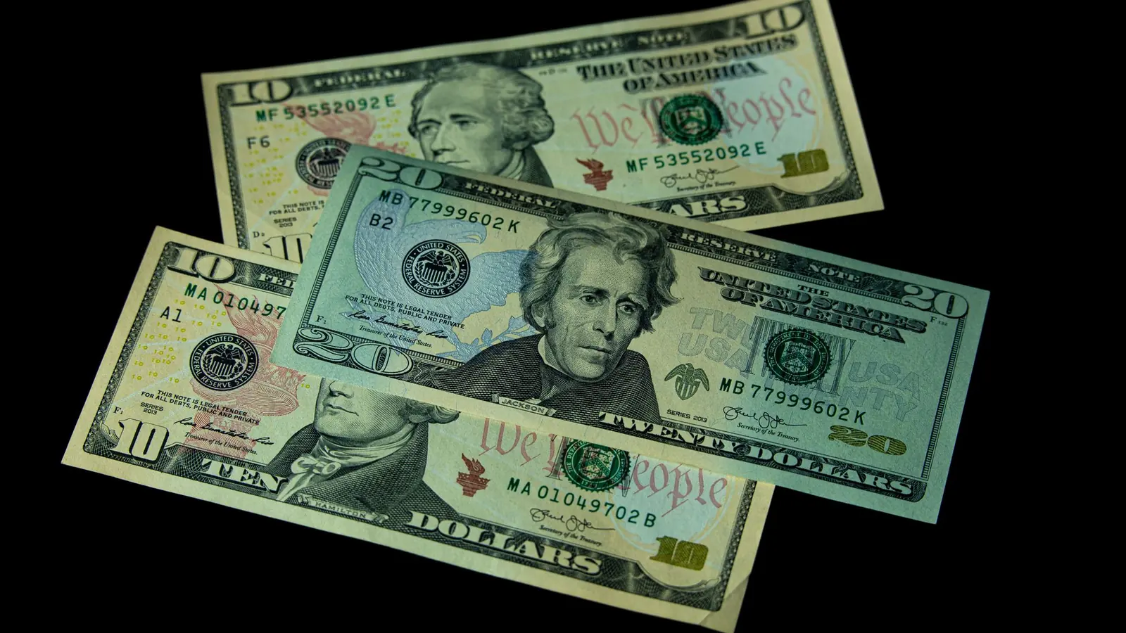US dollar bills spread on a dark surface