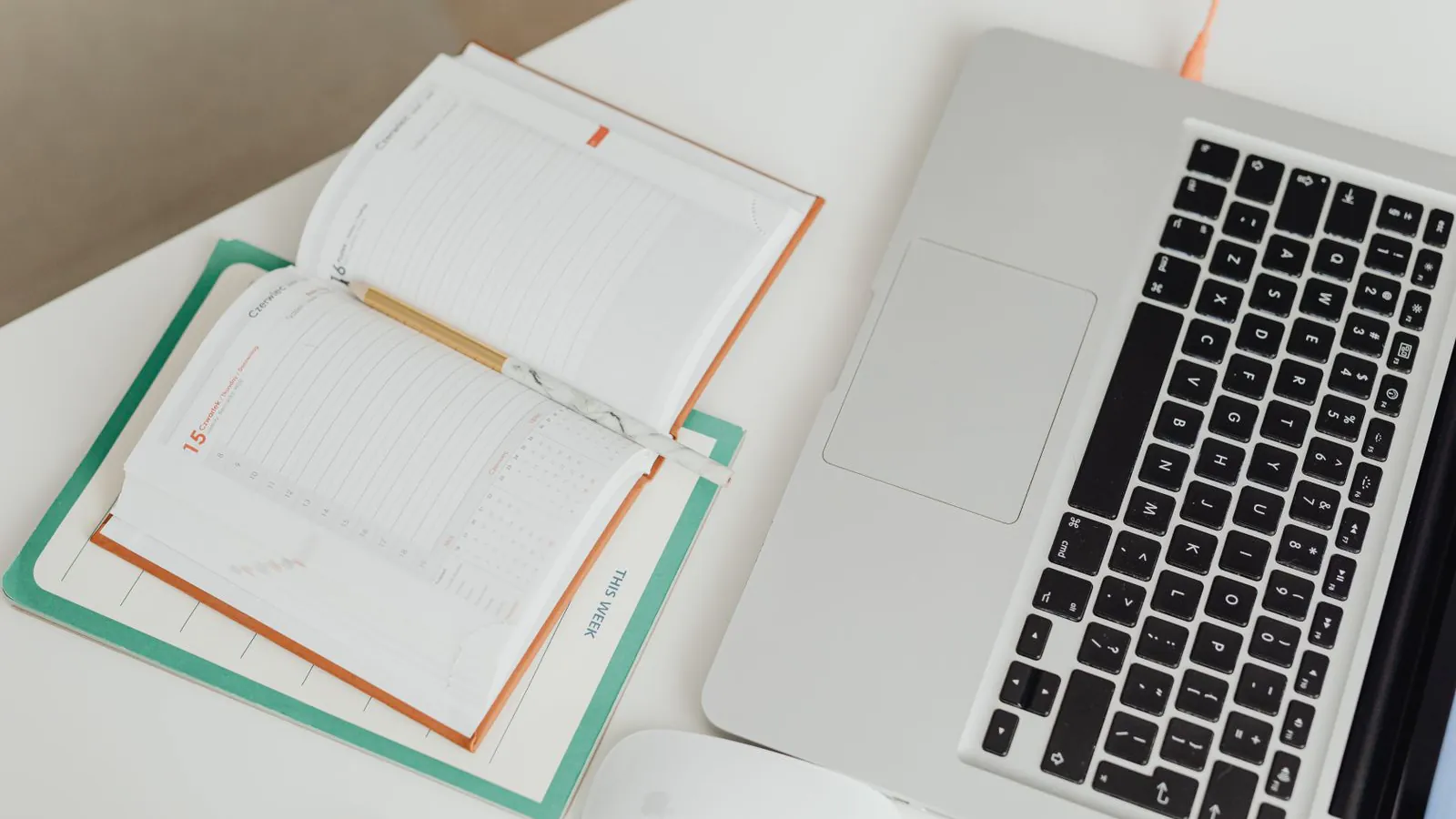 An open planner beside a laptop on a desk