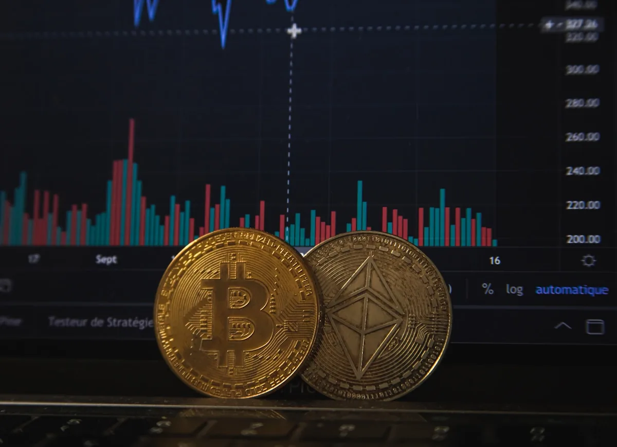 Bitcoin and Ethereum coins in front of a trading chart, representing the challenge fee returned on a first payout