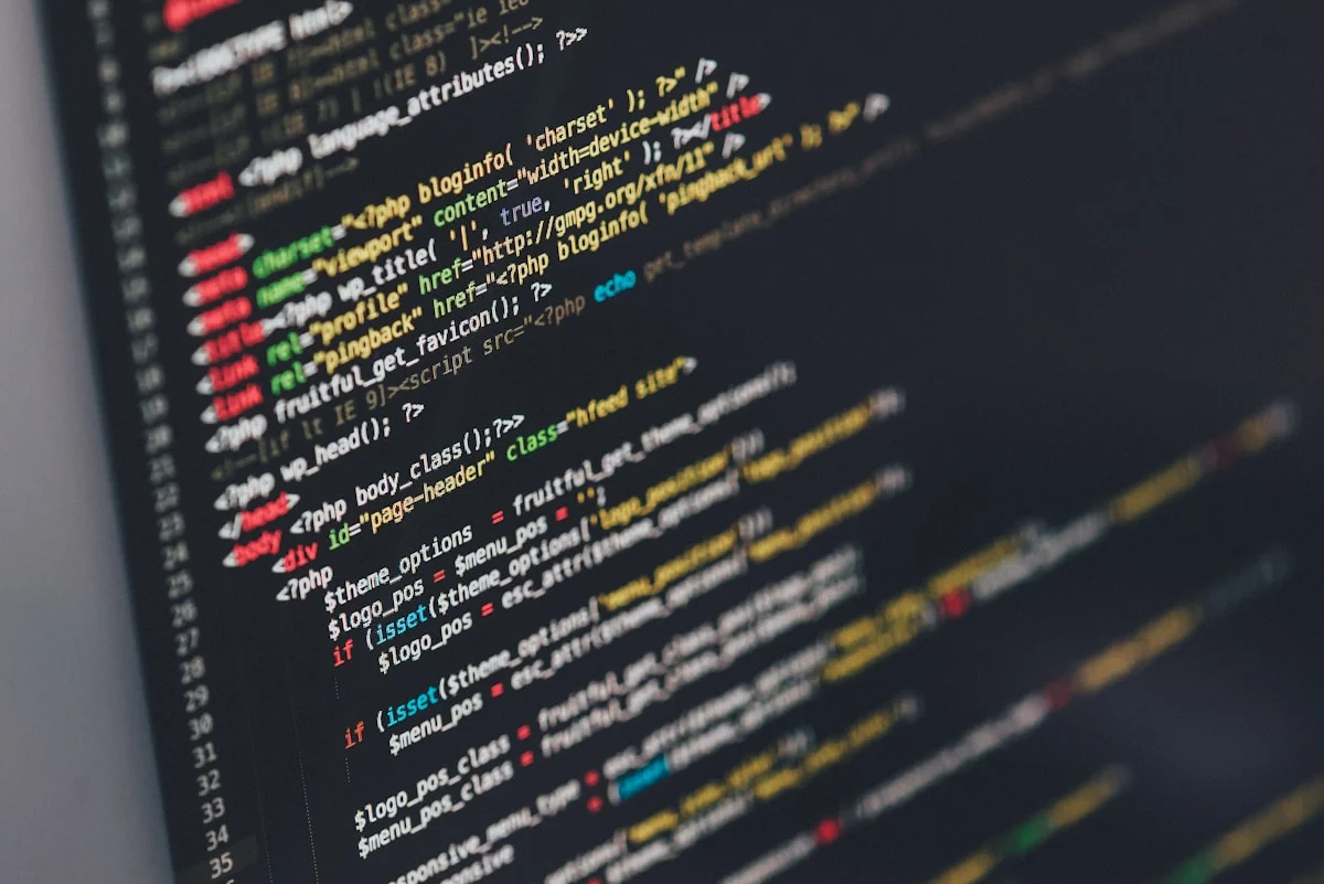 Developer writing trading bot code on a laptop, with multiple code files open and a dark terminal window visible.