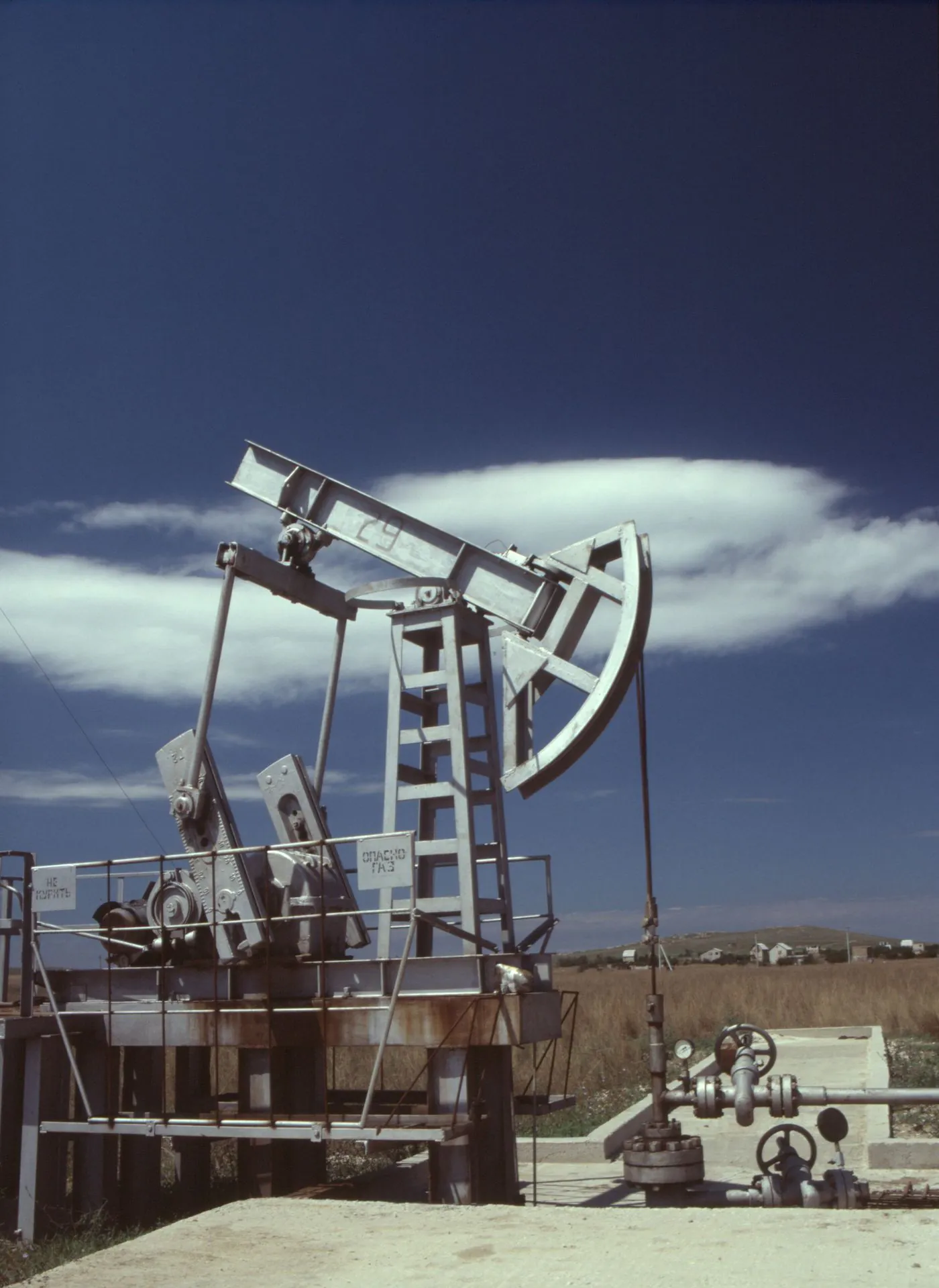An onshore oil pump jack extracting crude oil against a clear sky