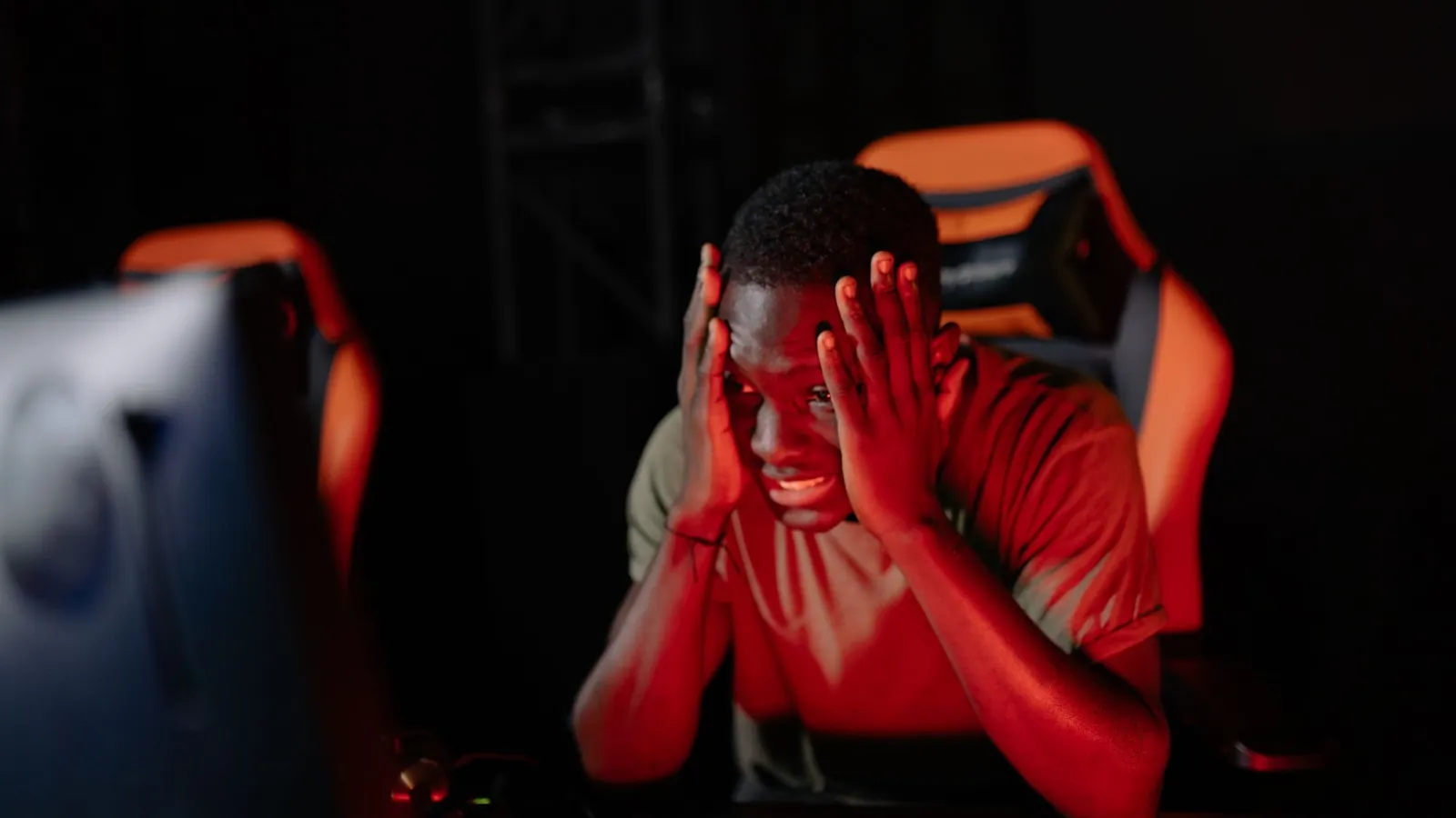 A stressed trader with his head in his hands in a dark room