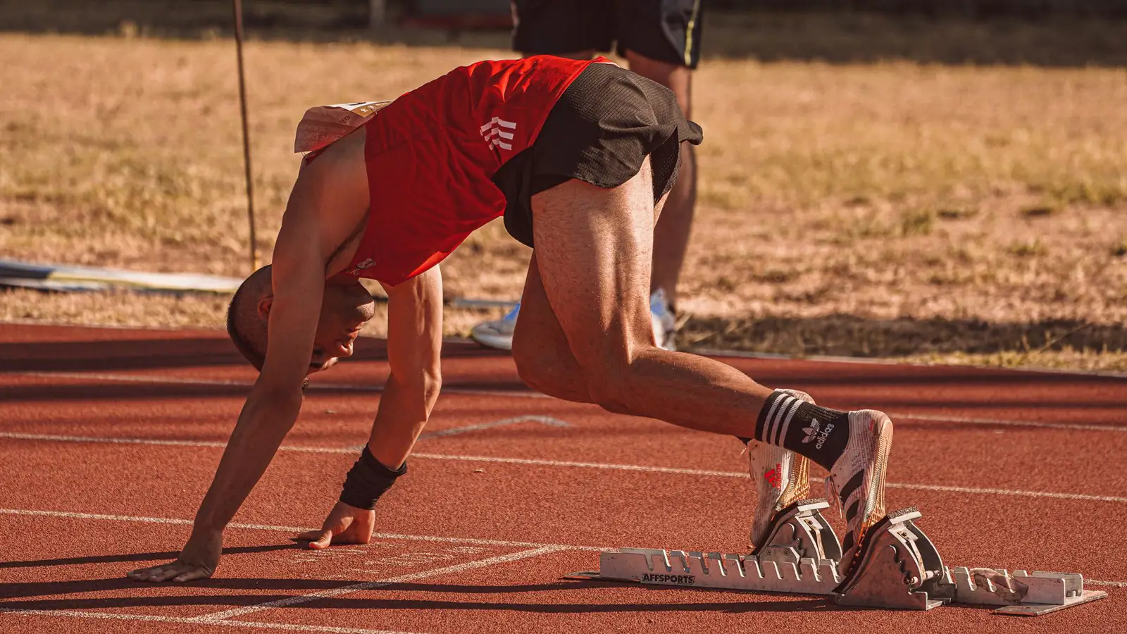 A sprinter in the starting position on a running track