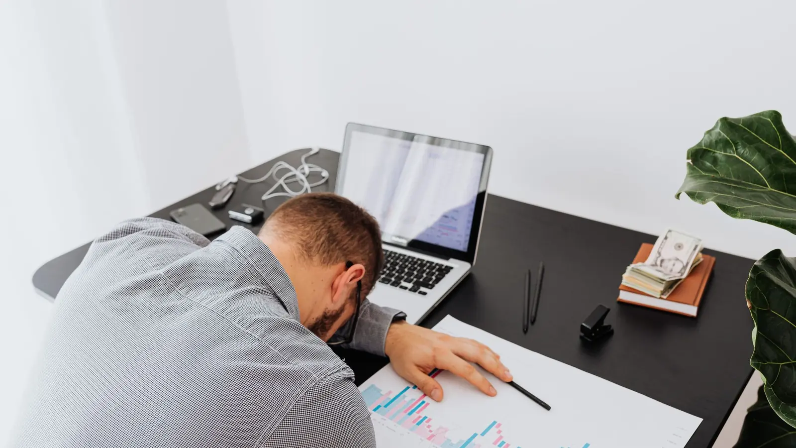 A trader slumped over a desk next to a laptop after a bad session