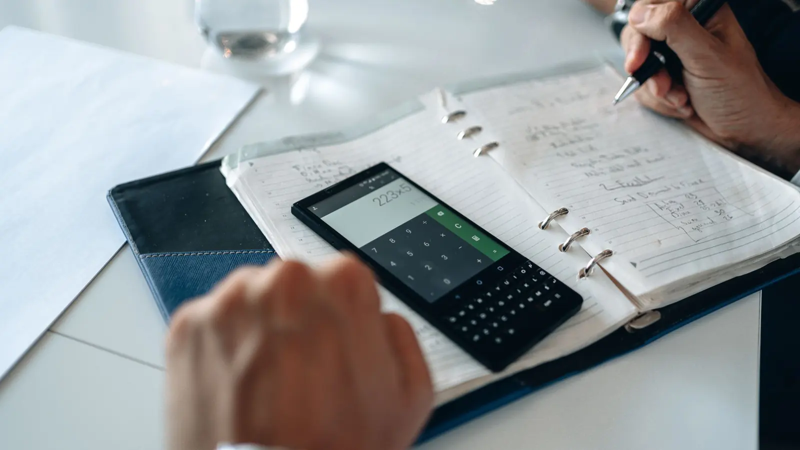 A trader working out position size with a calculator and a planner