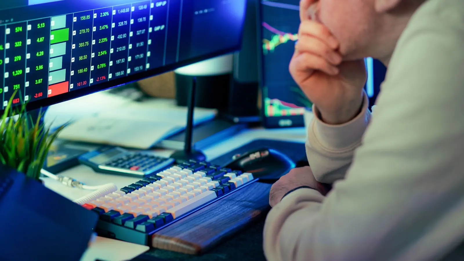 A trader concentrating in front of screens at a desk