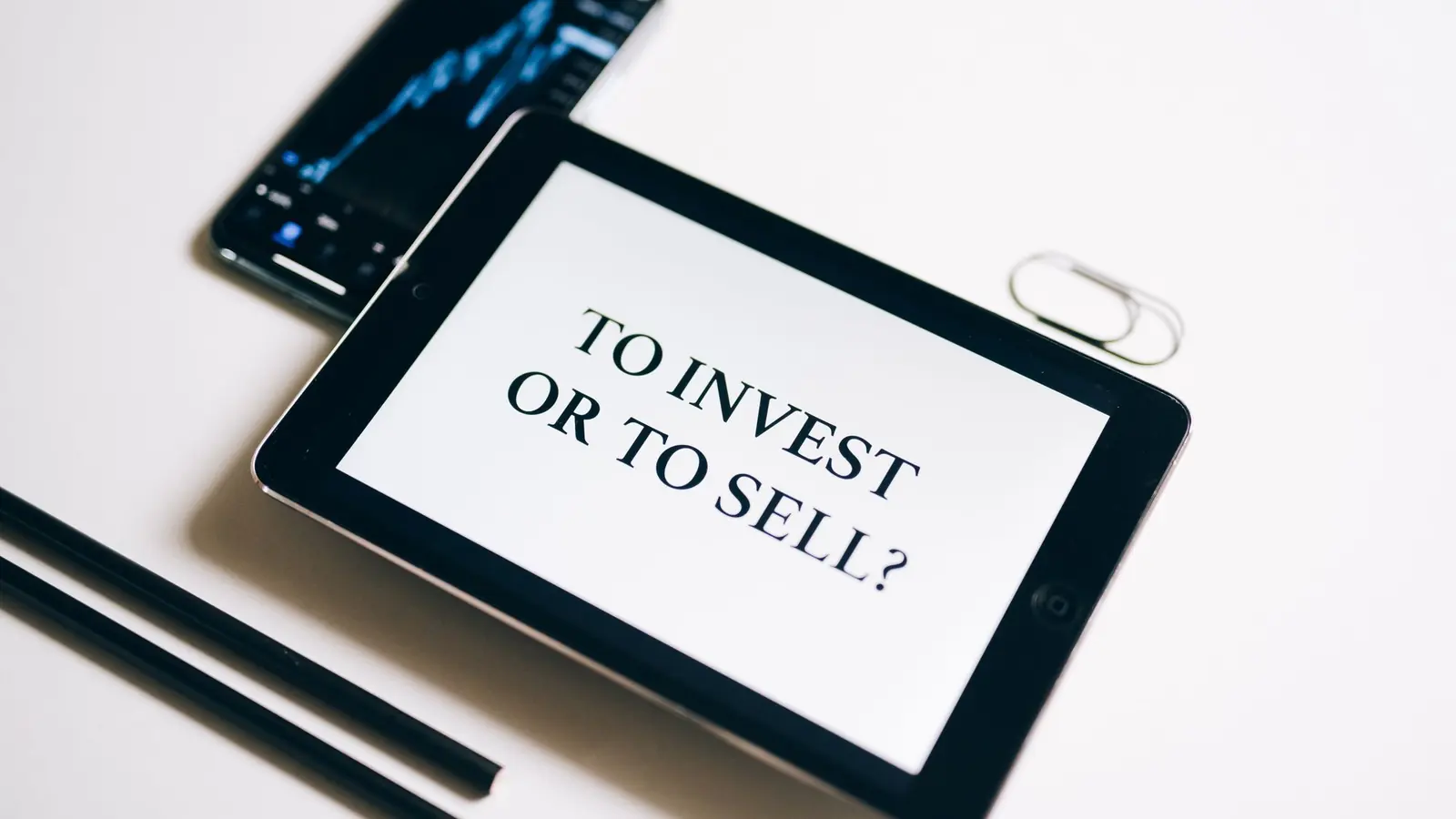A tablet showing the words to invest or to sell