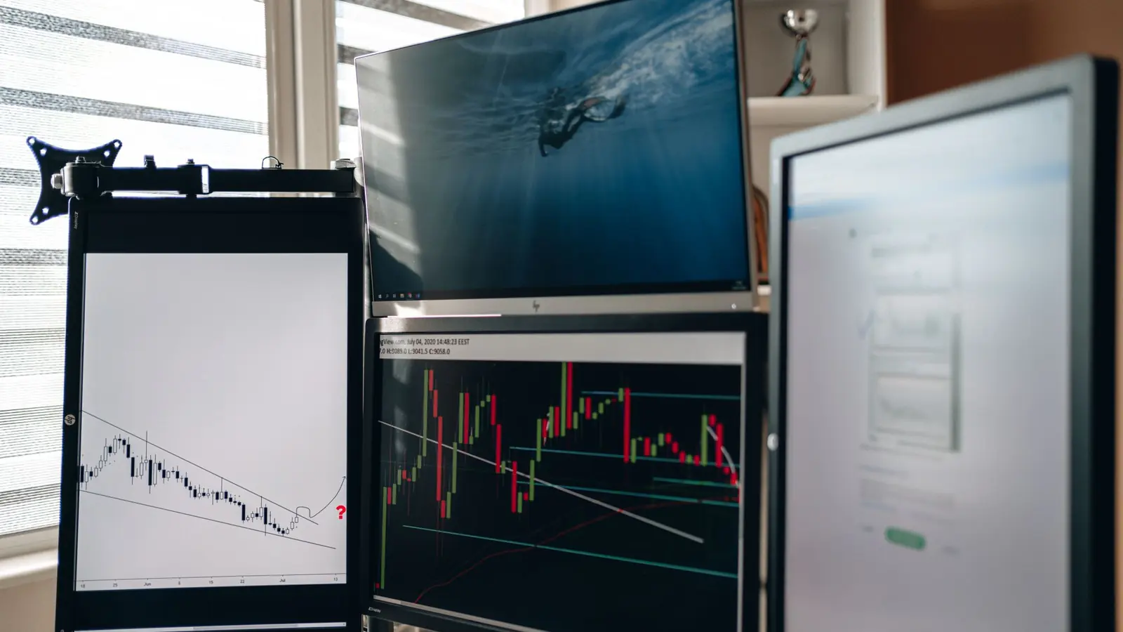 A trading desk with several monitors showing price charts