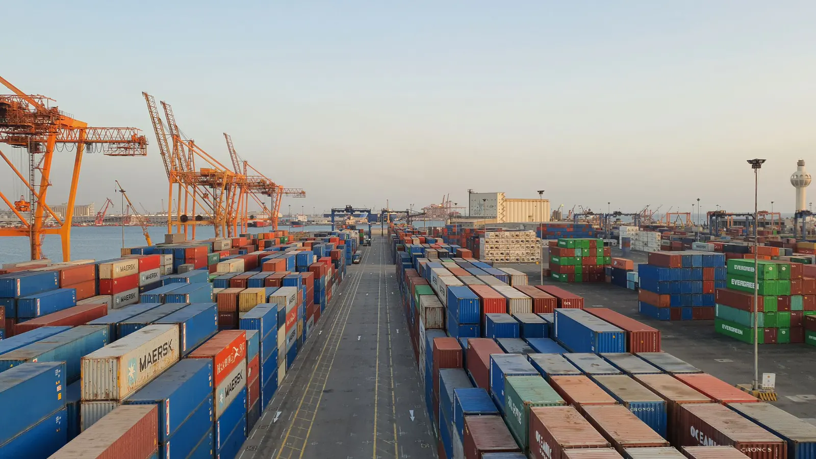 Aerial view of a container port with stacks of shipping containers and cranes