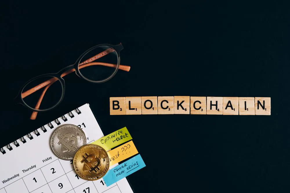 The word blockchain spelled in tiles beside crypto coins, representing how tokenized gold is issued on-chain