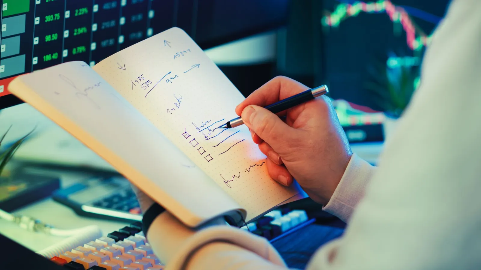 A trader writing notes while reviewing market data