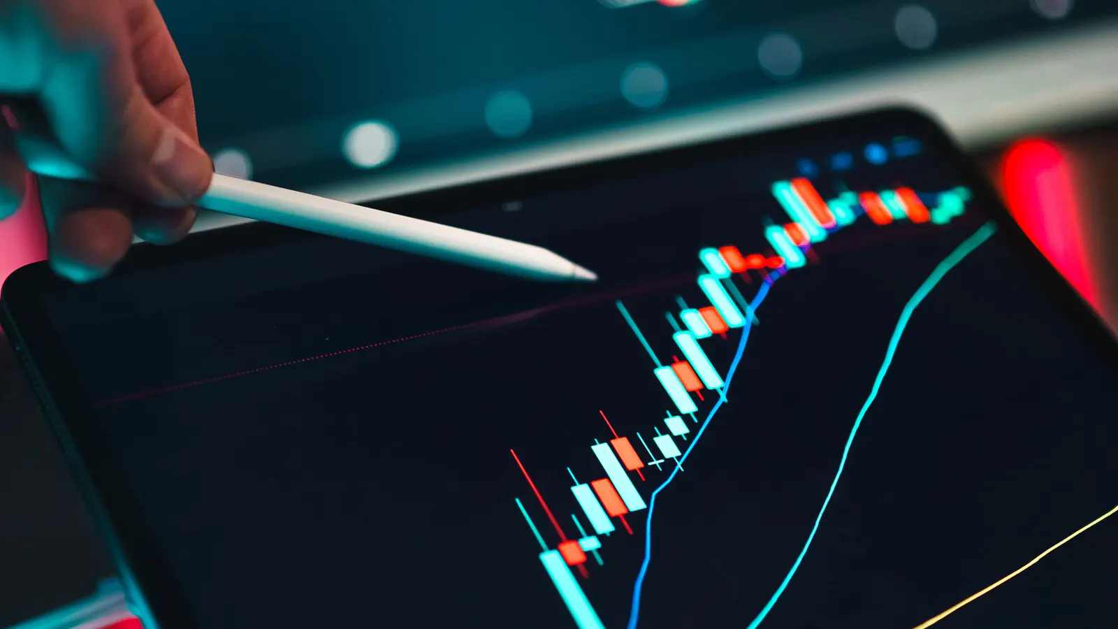 A stylus pointing at a candlestick chart on a tablet screen