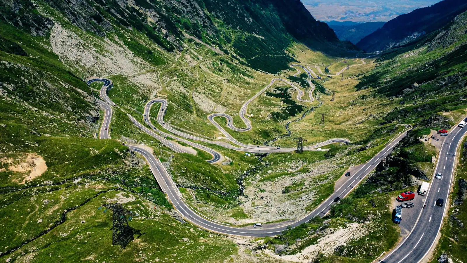 Aerial view of a long road winding through a green mountain valley