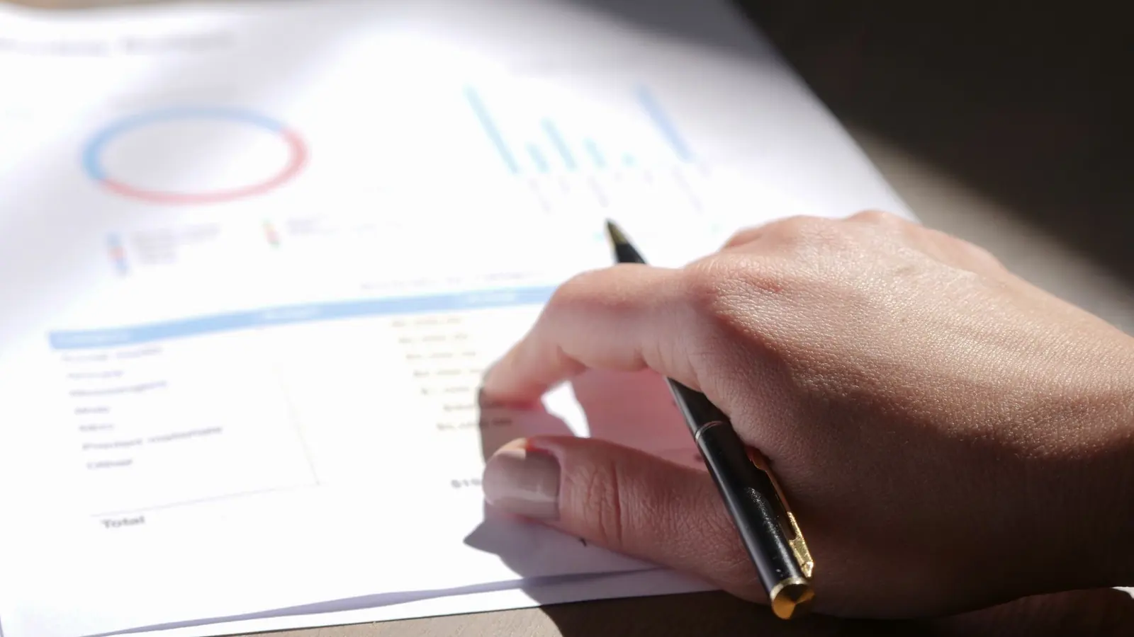 A hand with a pen reviewing a printed chart