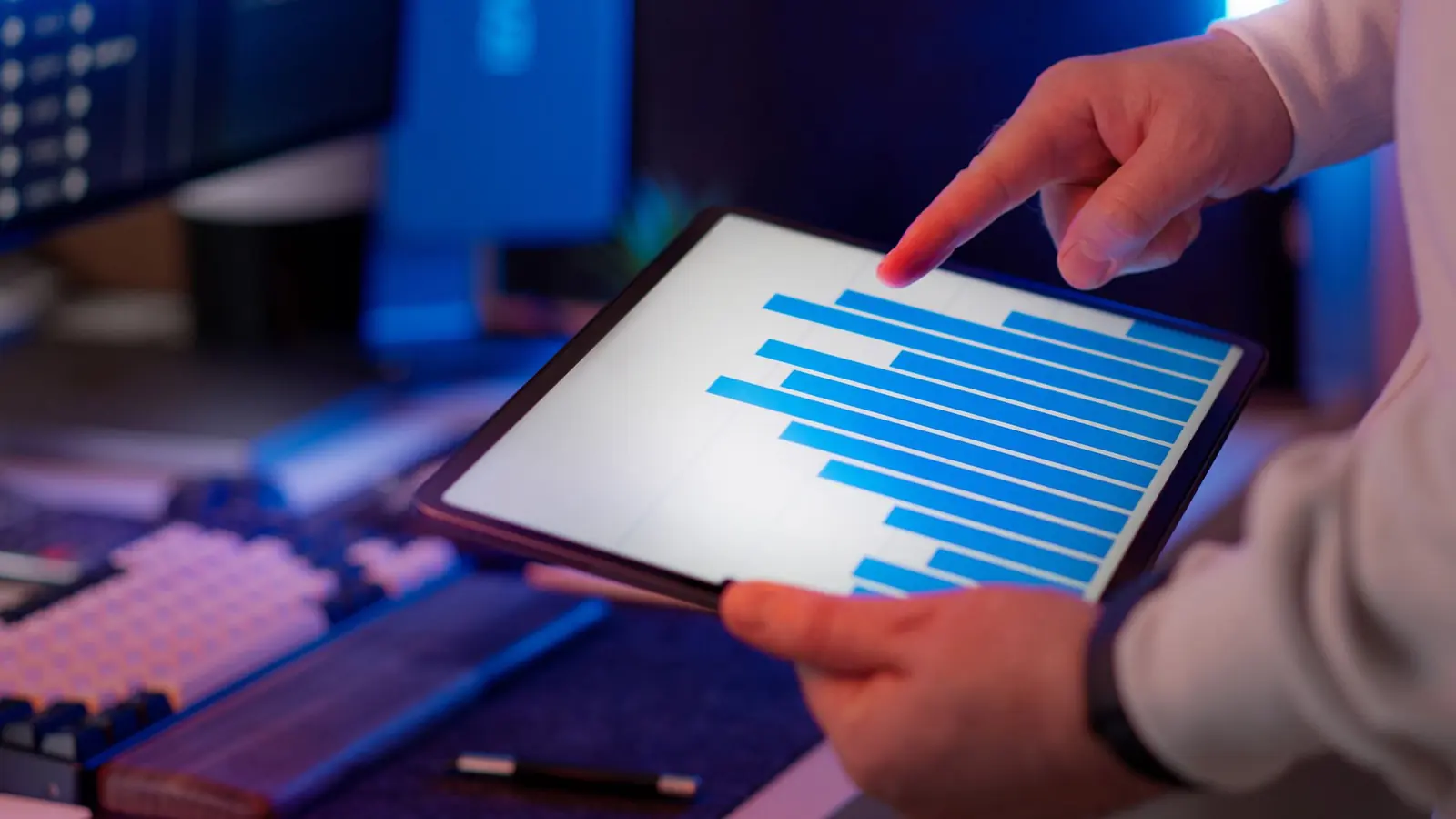 A hand pointing at a horizontal bar chart on a tablet