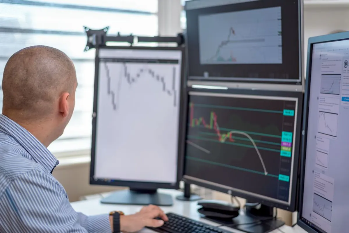 A trader analysing multiple currency pairs on a multi-monitor setup